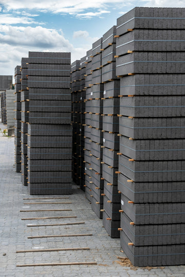 Stacks of gray pavers are neatly arranged outdoors.